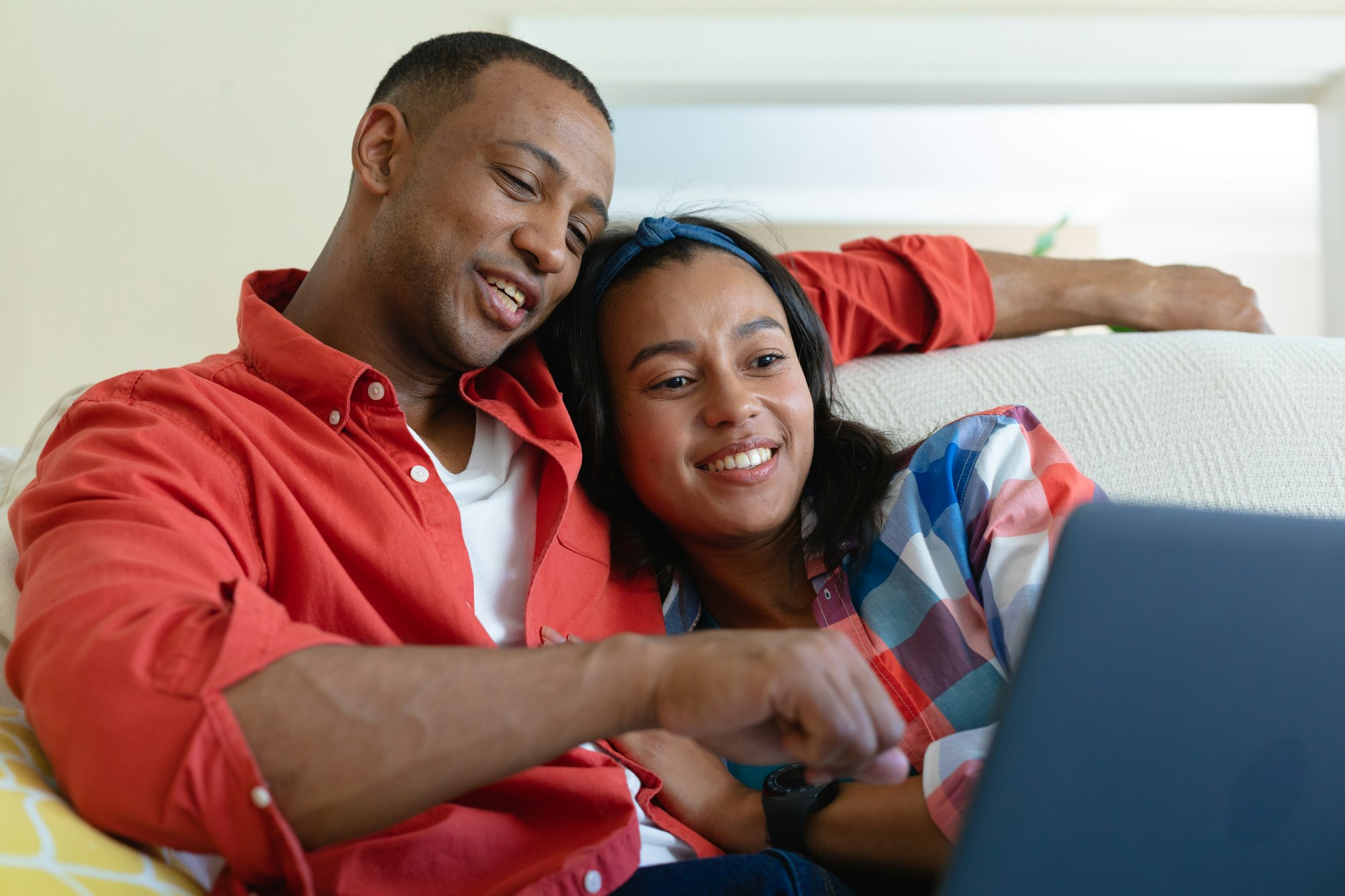 Smiling young african american couple watching laptop together at home